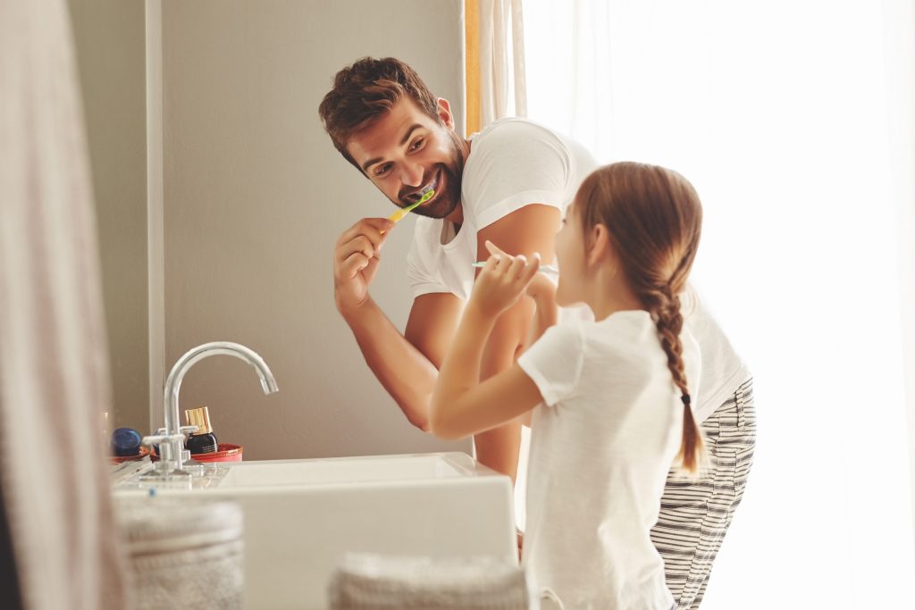 Papá e hija lavándose los dientes para evitar dientes amarillentos