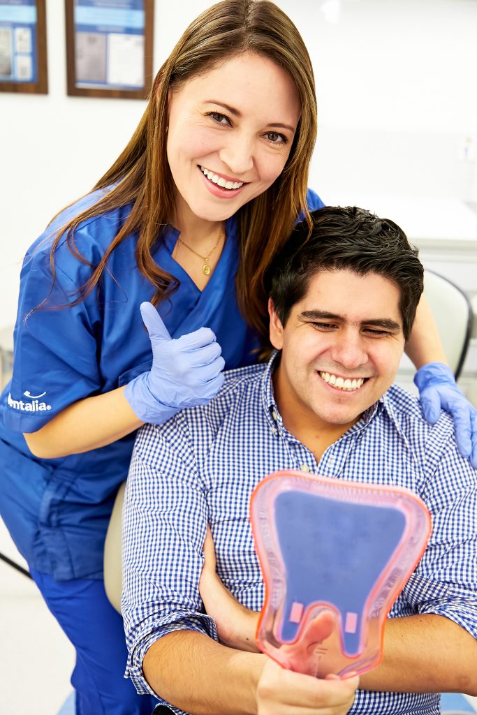 Dentista en dentalia con paciente satisfecho después de una limpieza dental profunda