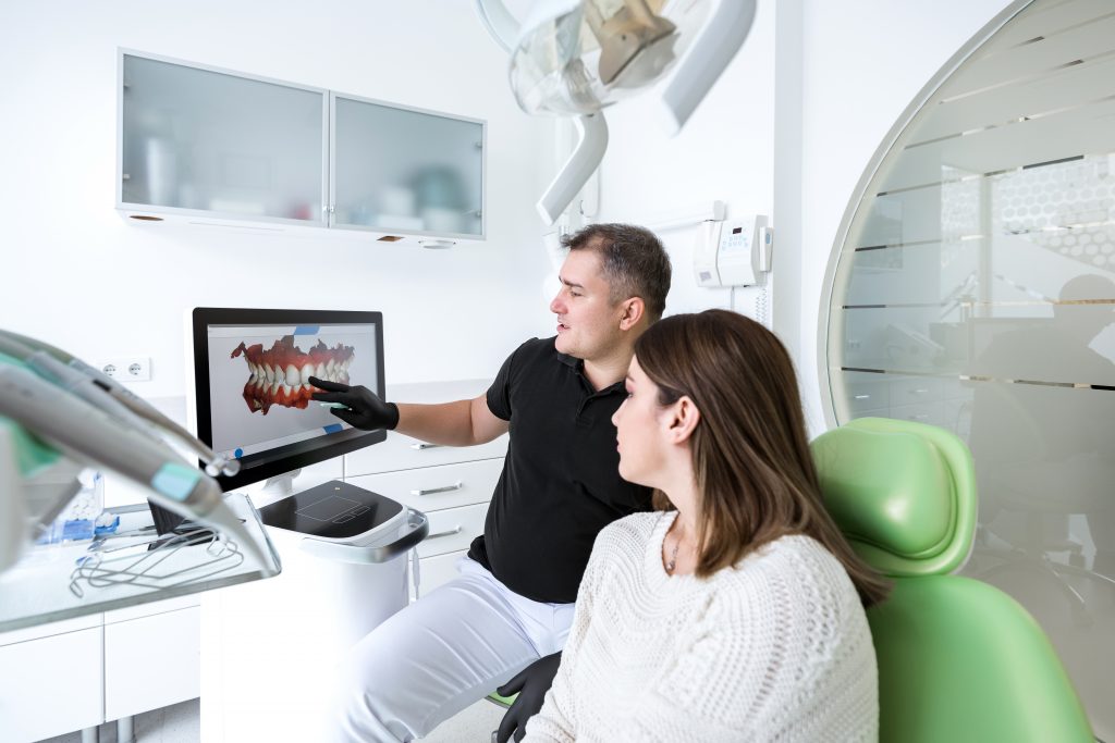 Dentista mostrando en computadora cómo funciona el tratamiento de alineadores Invisalign