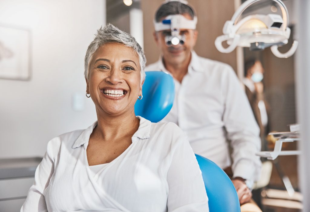 Mujer en consultorio dental mostrando una sonrisa con encías saludables y firmes