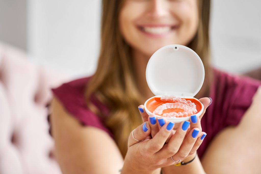 Chica mostrando sus alineadores dentales en su caja